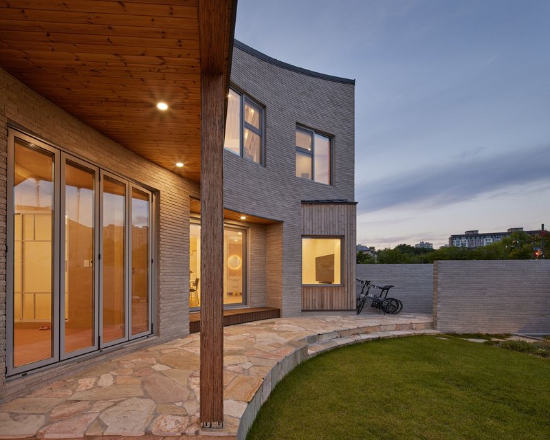 Rear courtyard with stone paving and timber column at dusk beneath a wood-lined soffit