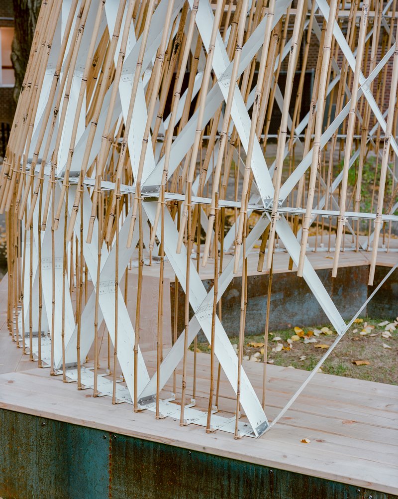 Corner detail of bamboo screen with white diagonal supports anchored on timber deck