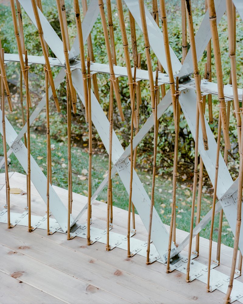 Close-up of bamboo poles and white aluminum bracing with green vegetation visible beyond
