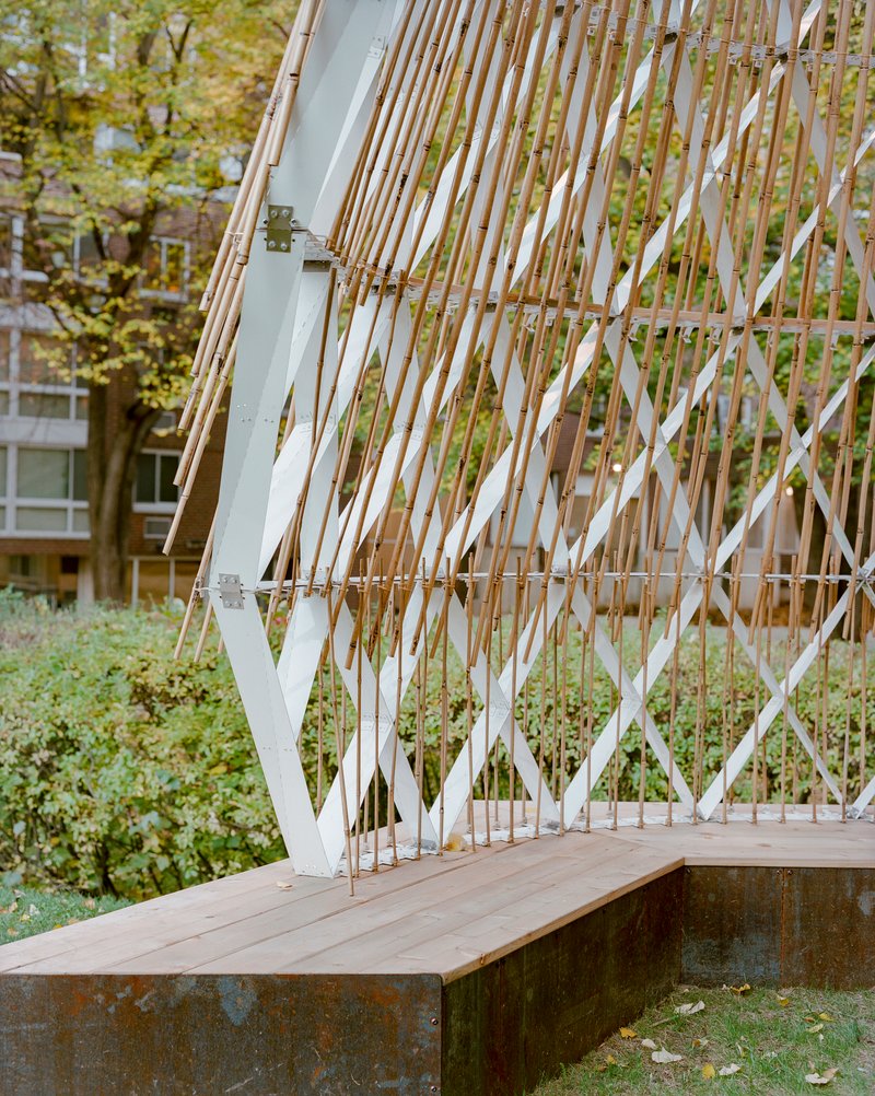 Detail of the angled lattice wall meeting the timber bench and rusted steel base
