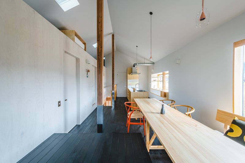 Dining space with vaulted ceiling and skylights running along dark timber floorboards