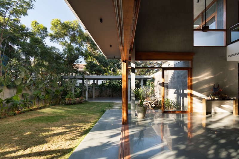 Corner veranda with timber columns and concrete soffit opening onto lawn and trees in morning sun