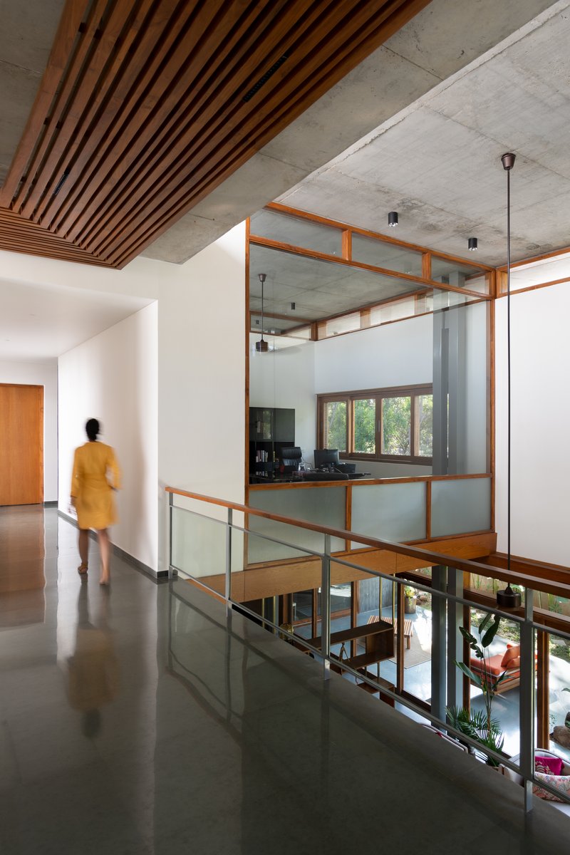Upper level hallway with timber slat ceiling and glass-railed opening overlooking the double-height space below