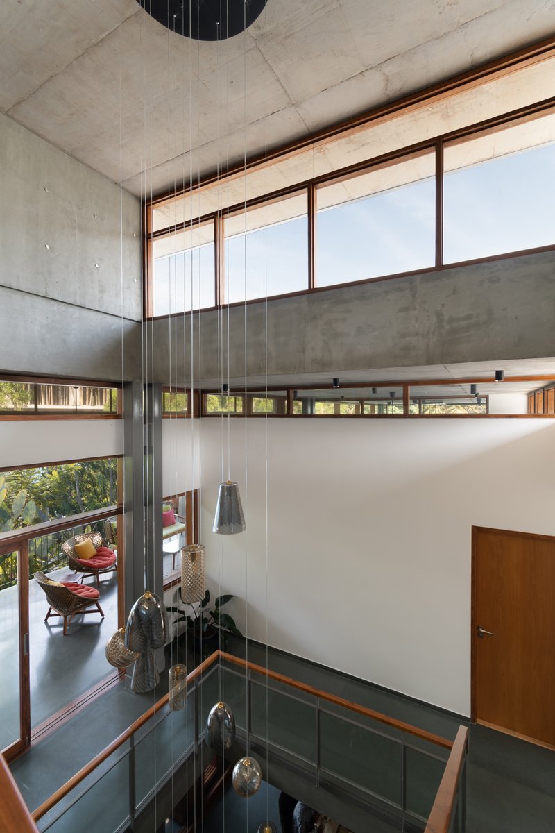 Double-height void with pendant lights descending through the space framed by timber-trimmed clerestory windows