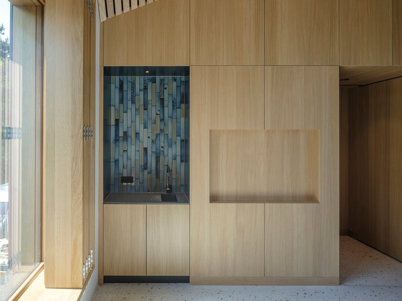 Built-in cabinetry with blue tile backsplash niche set within light wood paneling