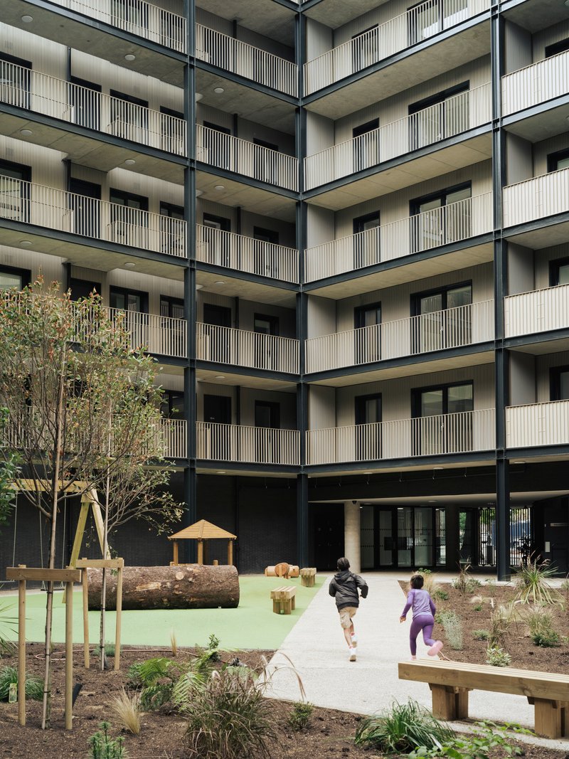 Interior courtyard with timber play structures and planted beds where two children are running