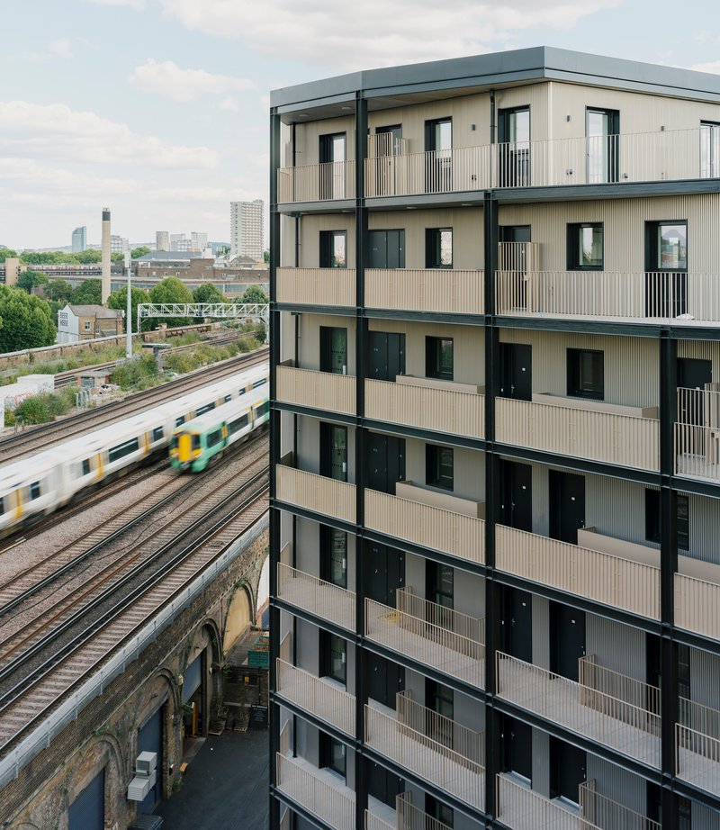 Facade overlooking railway tracks with commuter train passing in motion blur below
