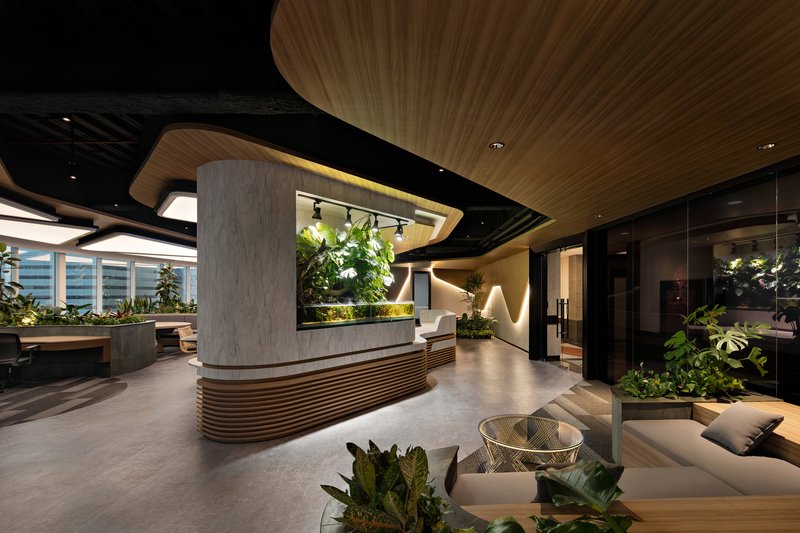 Reception desk with concrete and wood slat base beneath a curved timber ceiling with integrated planters