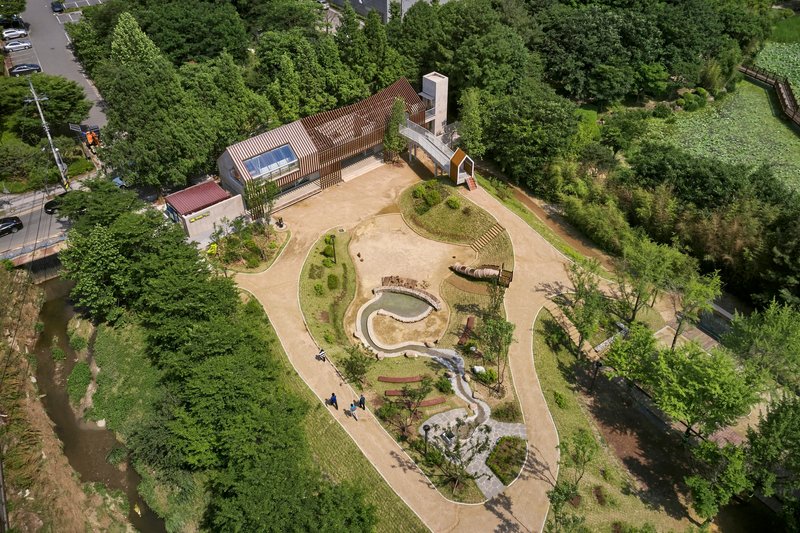 Aerial view of the serpentine water feature and planted mounds surrounded by forest canopy