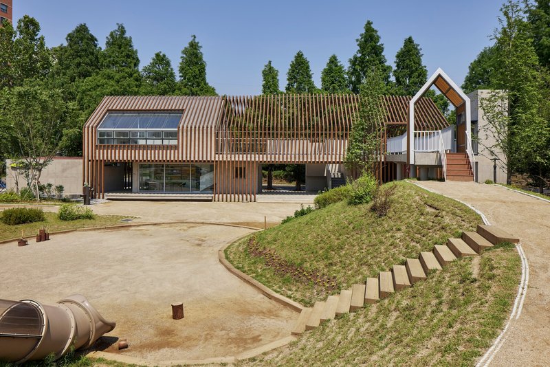 Front elevation with vertical timber slats screening the glazed facade and a house-shaped volume beyond