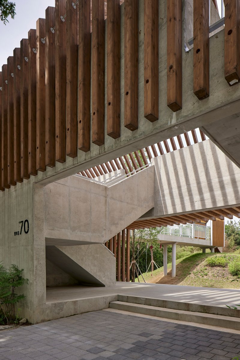 Vertical timber louvers casting stripes of shadow on concrete walls and steps below