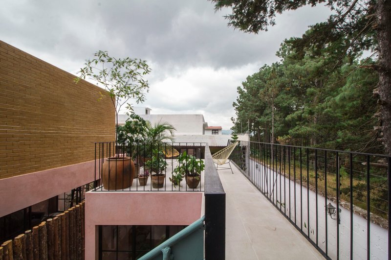 Upper terrace with metal railings, potted plants, and hammock under overcast sky