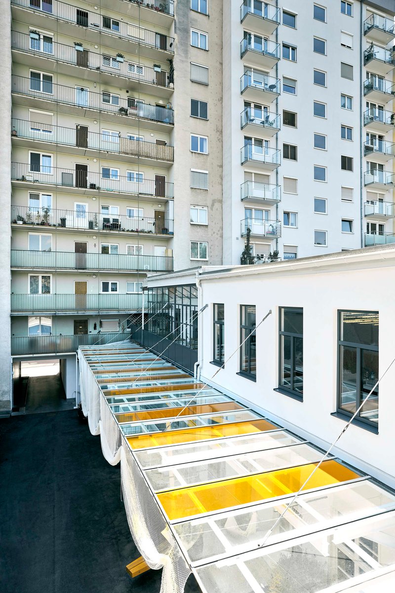 Aerial view of white metal grid roof with clear and yellow glazing panels between residential buildings