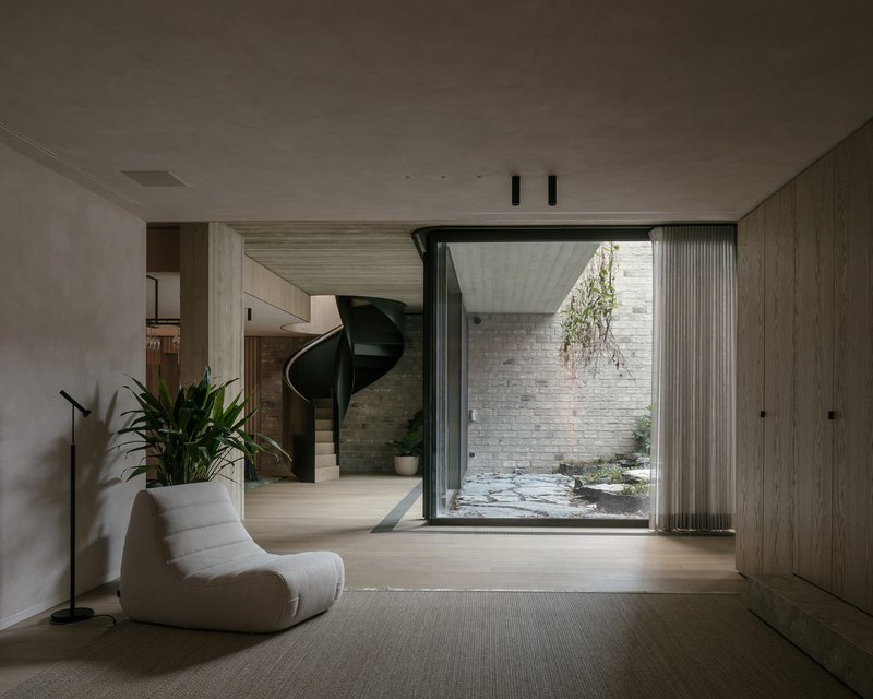 Interior room with light timber flooring opening to a small courtyard with brick walls and hanging greenery