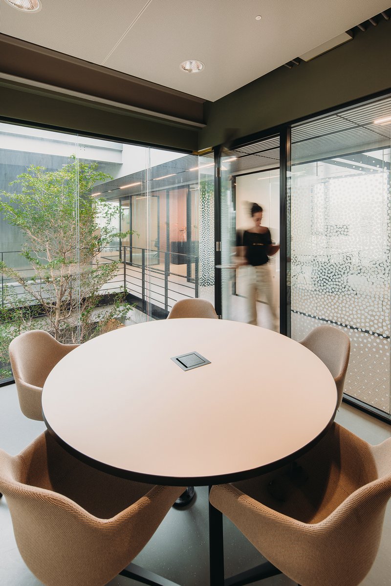 Round meeting table with view to interior courtyard garden through floor-to-ceiling glazing