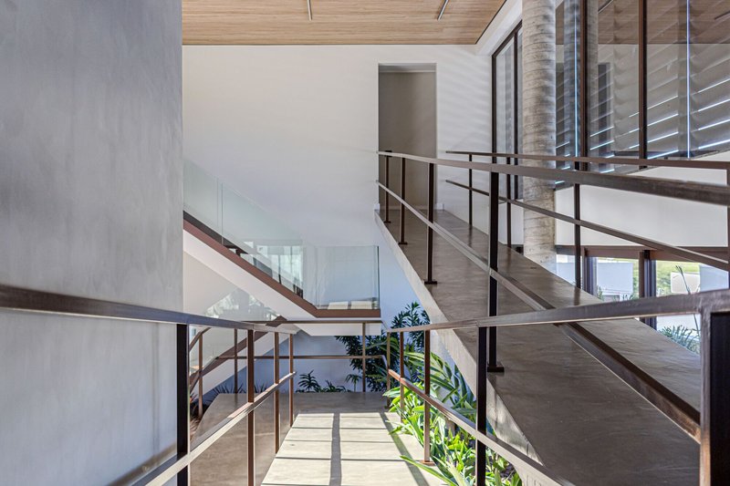 Multilevel atrium with steel railings, timber ceilings and planted beds receiving dappled sunlight