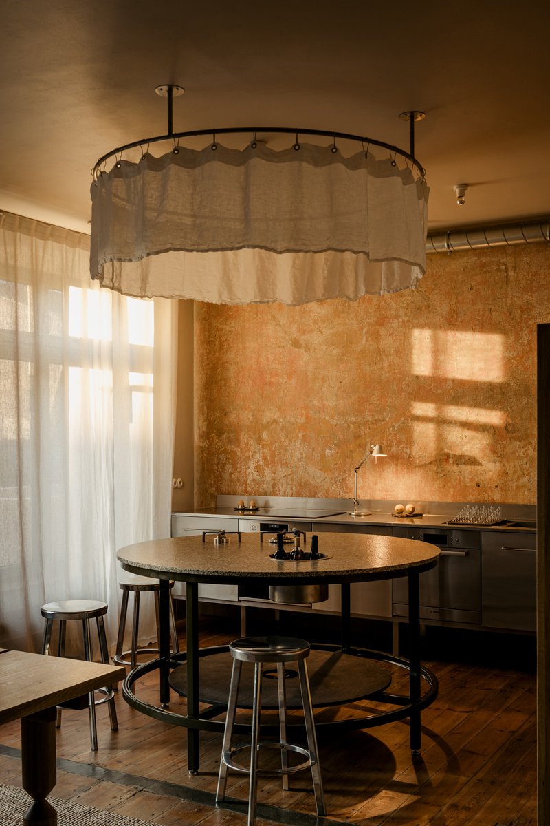 Kitchen with circular fabric canopy light fixture above round table and textured plaster wall behind