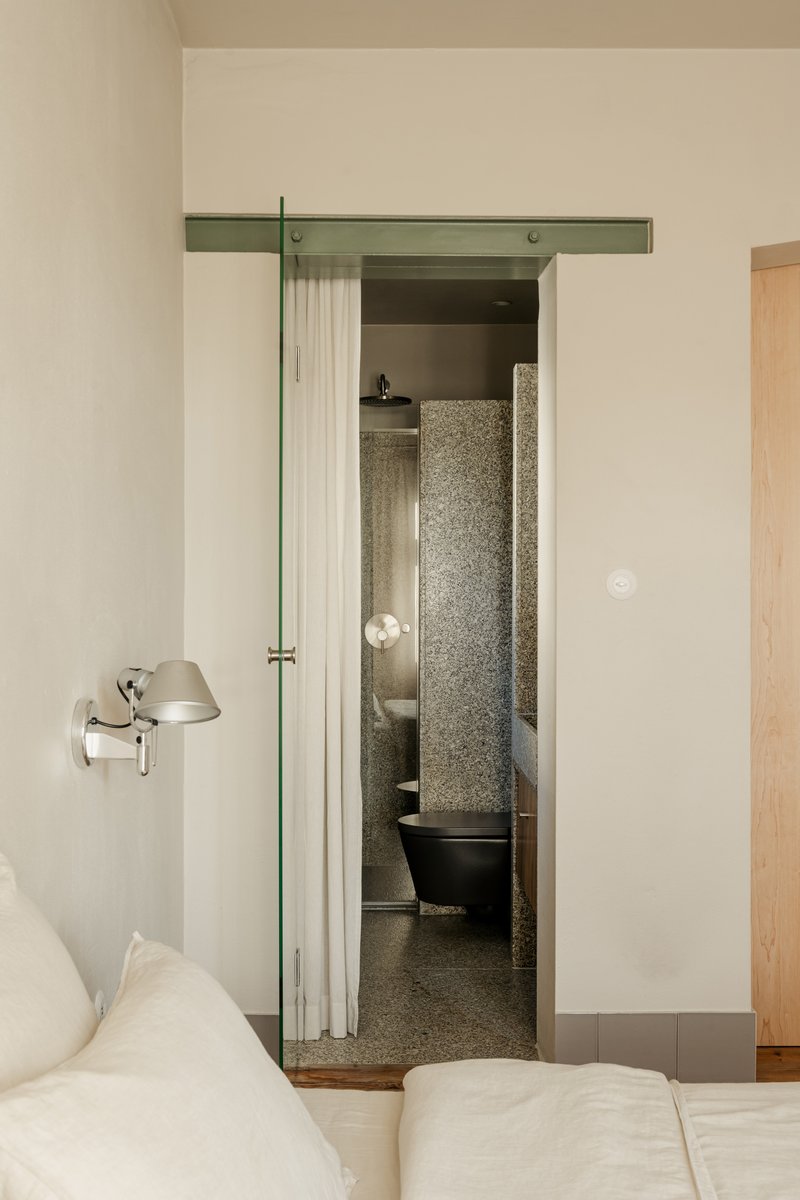 Bedroom view through doorway into bathroom with terrazzo flooring and freestanding black tub