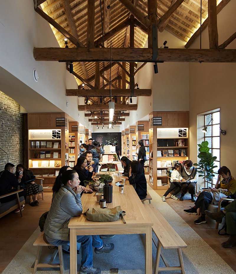 Central seating area with timber benches beneath vaulted ceiling with heavy timber beams and track lighting