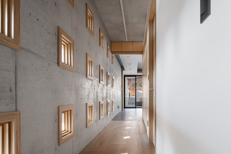 Corridor with timber-framed niches in board-formed concrete wall under exposed ceiling soffit