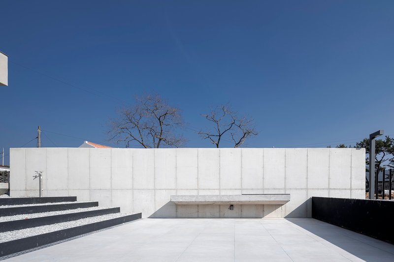 Concrete courtyard wall with recessed steps and sunken pool area beneath bare winter trees