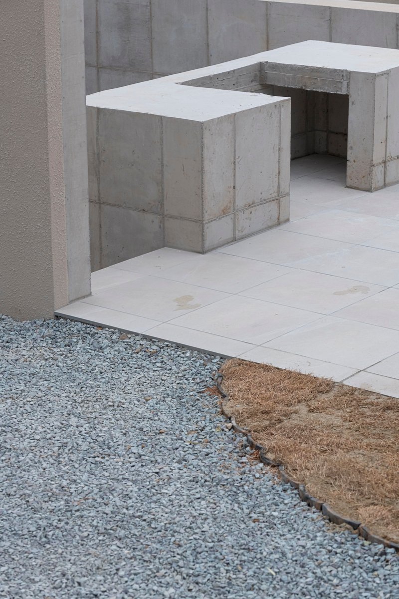 Board-formed concrete seating elements flanking gravel and paved stone ground plane