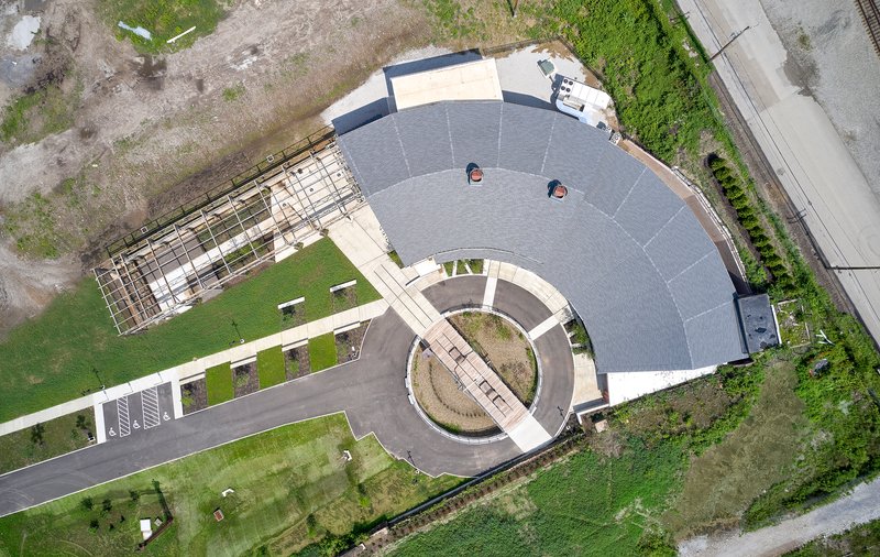 Aerial view of the curved building with a circular courtyard and solar panel roof surrounded by landscaping