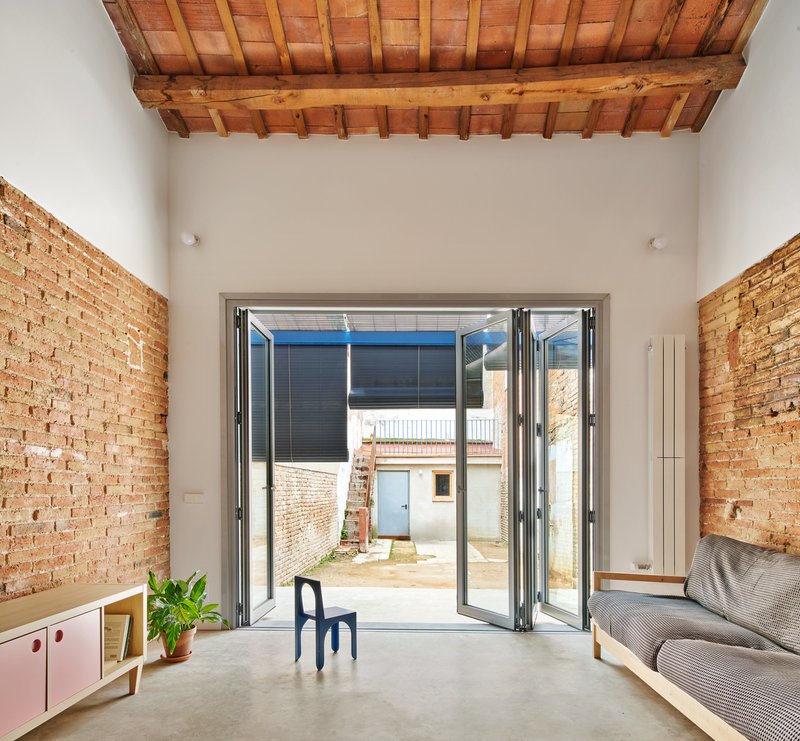 Folding glass doors opening to courtyard flanked by exposed brick walls under timber and tile roof