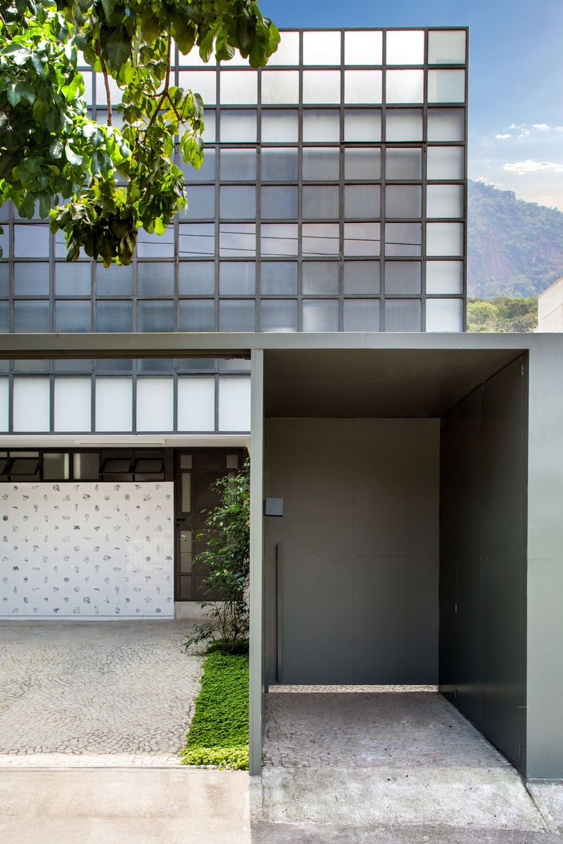Street facade showing translucent glass block wall above a dark recessed entrance and patterned tile courtyard