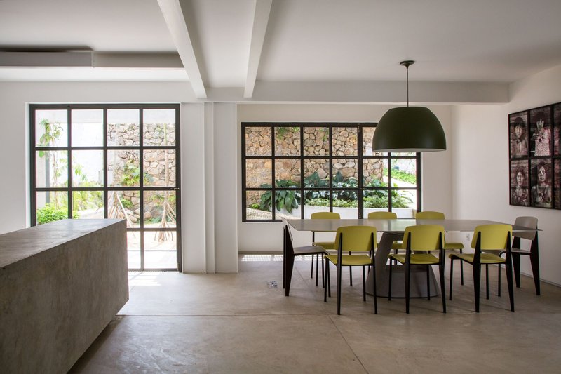 Dining area with concrete kitchen island and steel-framed windows overlooking a stone wall garden