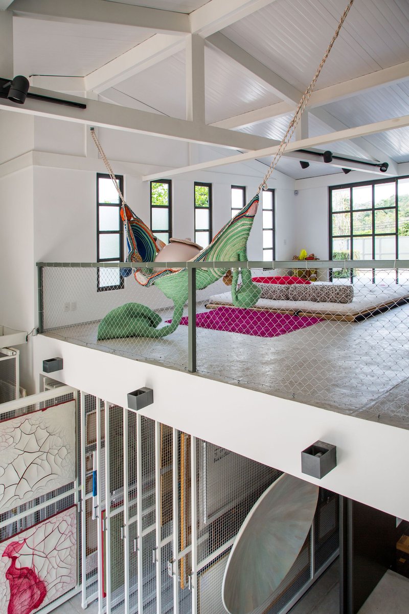 Upper-level lounge with exposed timber ceiling beams, wire mesh balustrade and suspended hammock