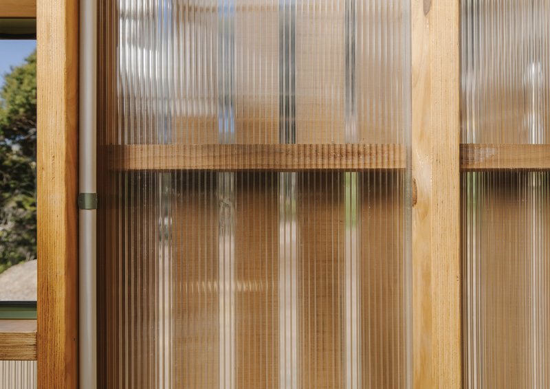 Close-up of fluted polycarbonate sliding door panel with timber frame and horizontal rail detail