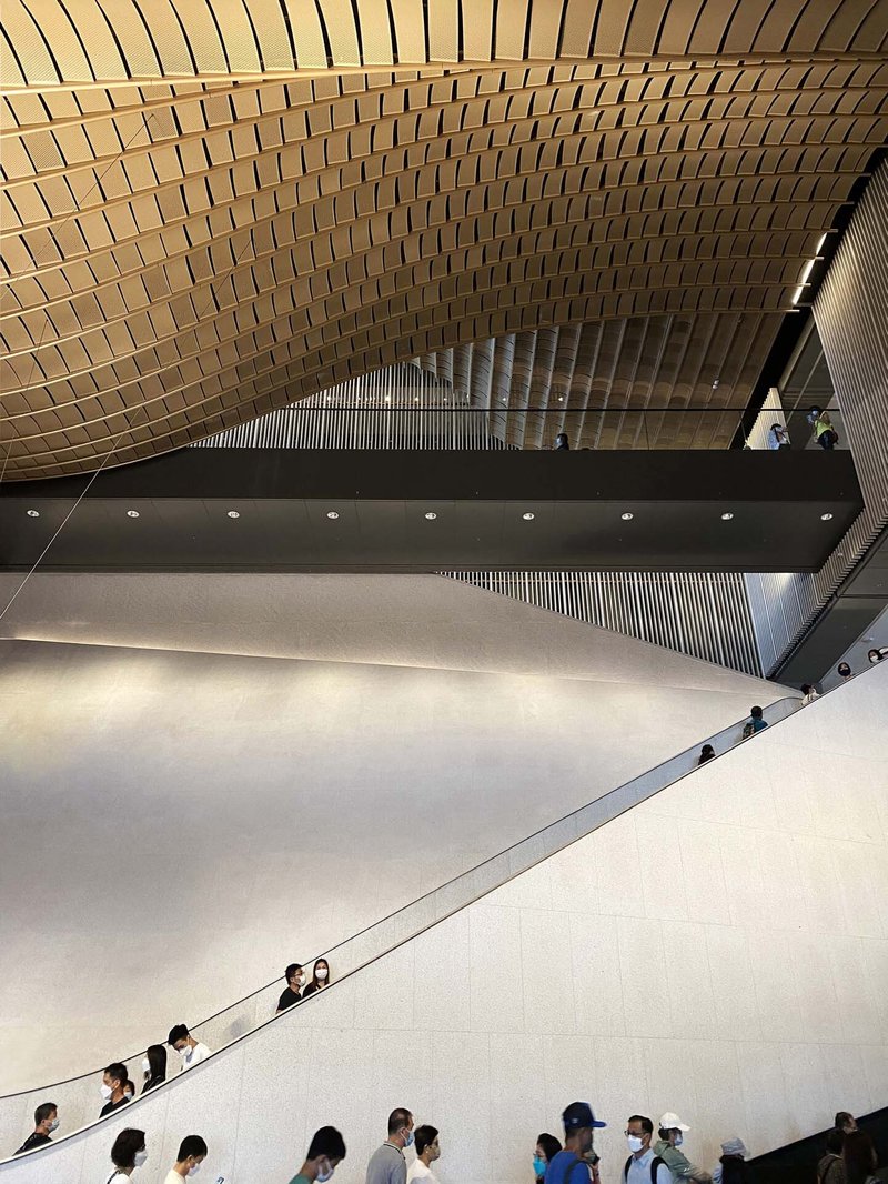 Overhead view of the white sloped wall with visitors ascending the adjacent staircase