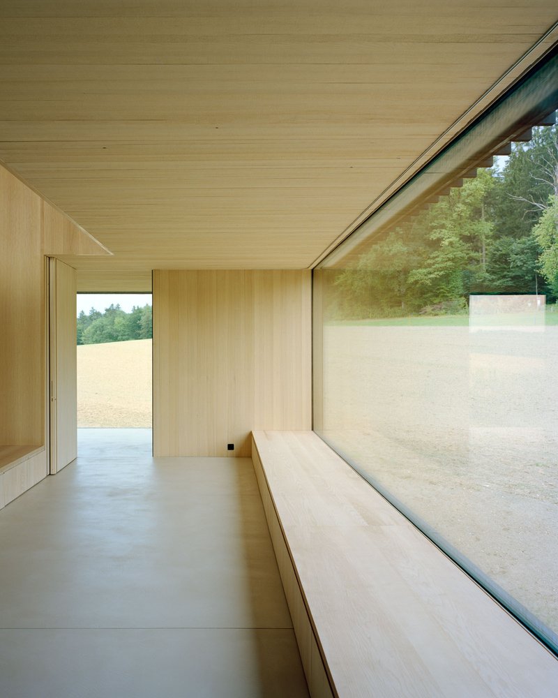 Interior room with continuous window bench looking onto the sloping sand courtyard beyond