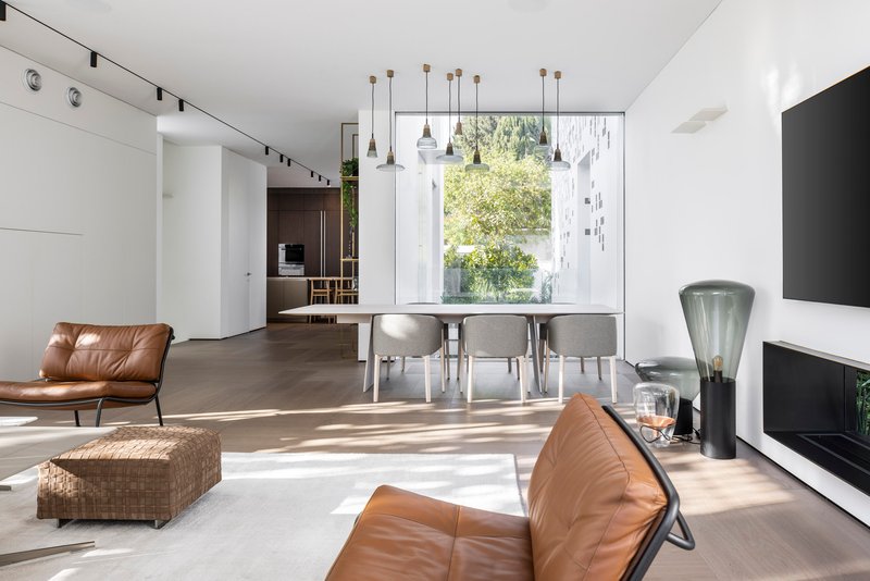 Open living and dining space with leather seating and pendant lights overlooking garden window
