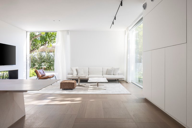 Open living room with wide plank oak flooring and floor-to-ceiling glazing overlooking garden greenery