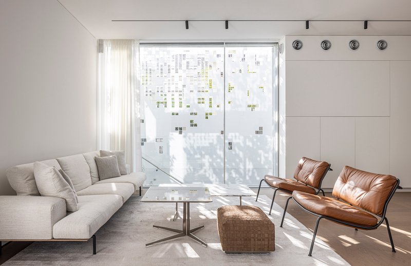 Living area with patterned perforated facade casting filtered shadows across seating and polished concrete floor