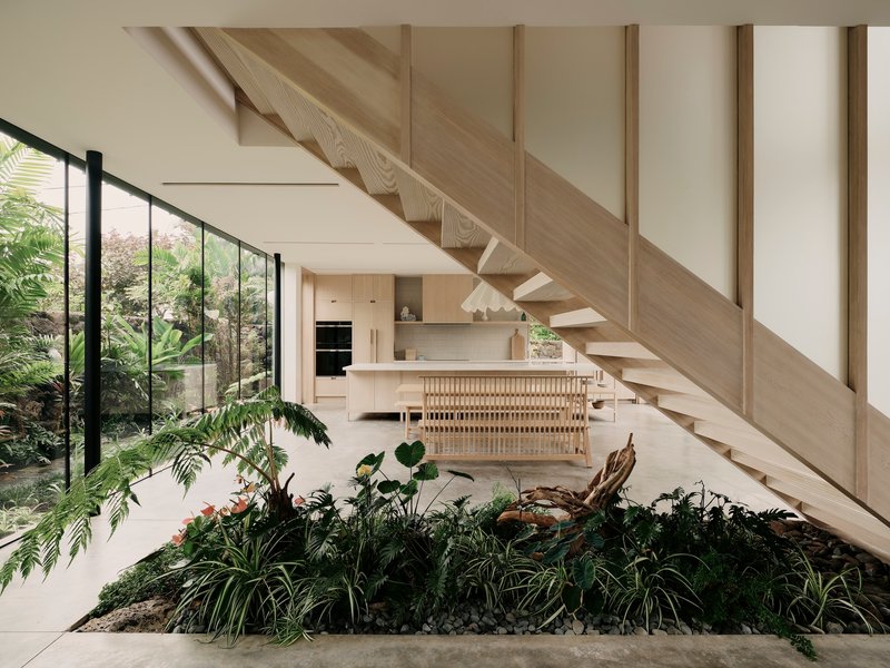 Interior planted bed beneath the timber staircase with kitchen island visible beyond