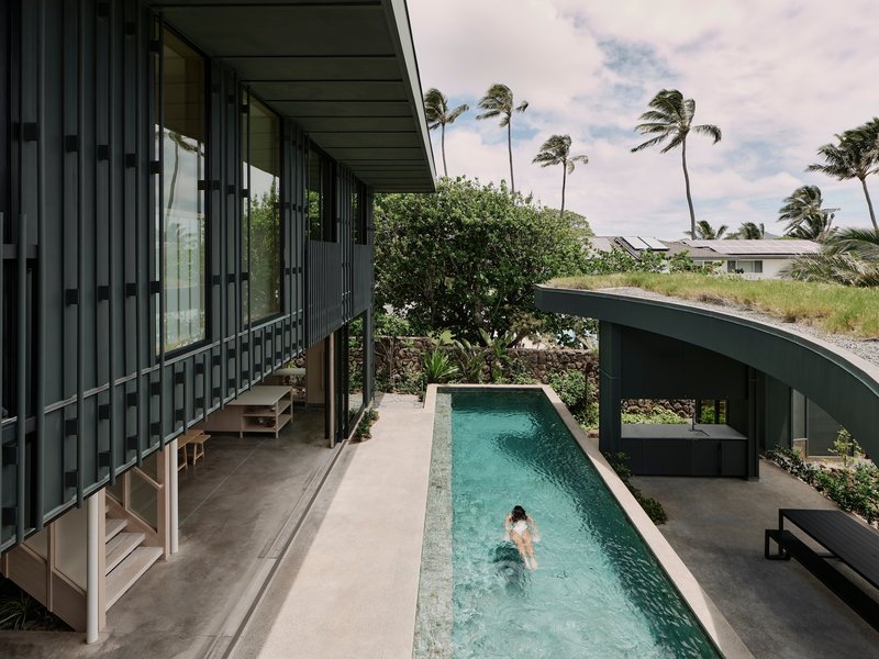 Covered upper terrace overlooking the lap pool where a swimmer glides through the water