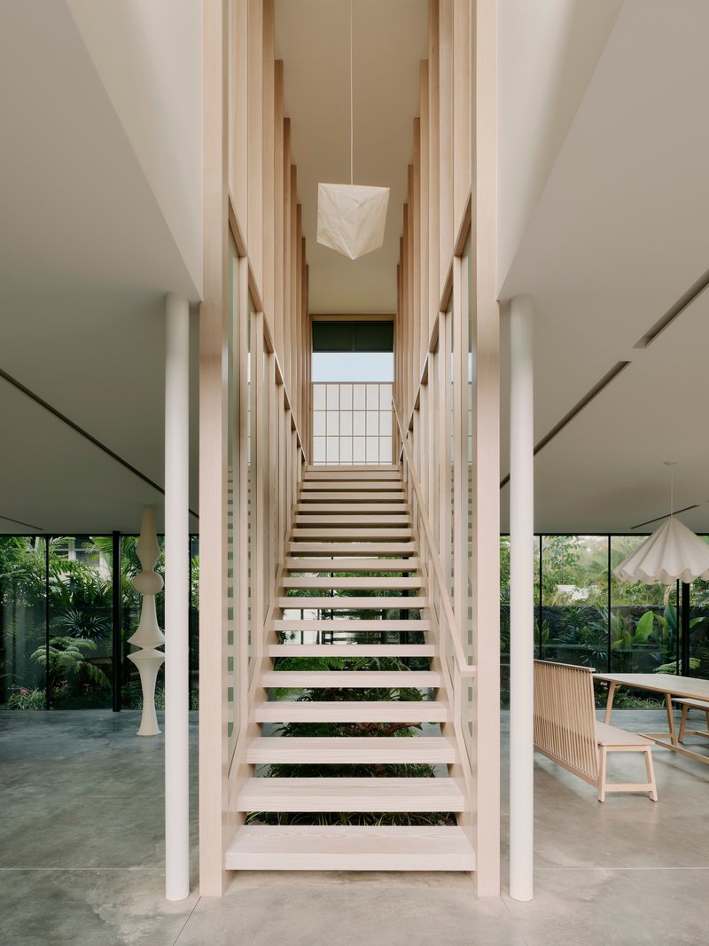Timber staircase with open treads flanked by white columns and vertical timber slats