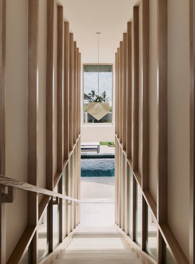 Descending staircase framed by vertical timber battens with view to pool and palms beyond
