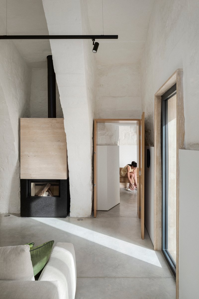 Corner fireplace with black metal hood and timber surround framing a view through an open doorway