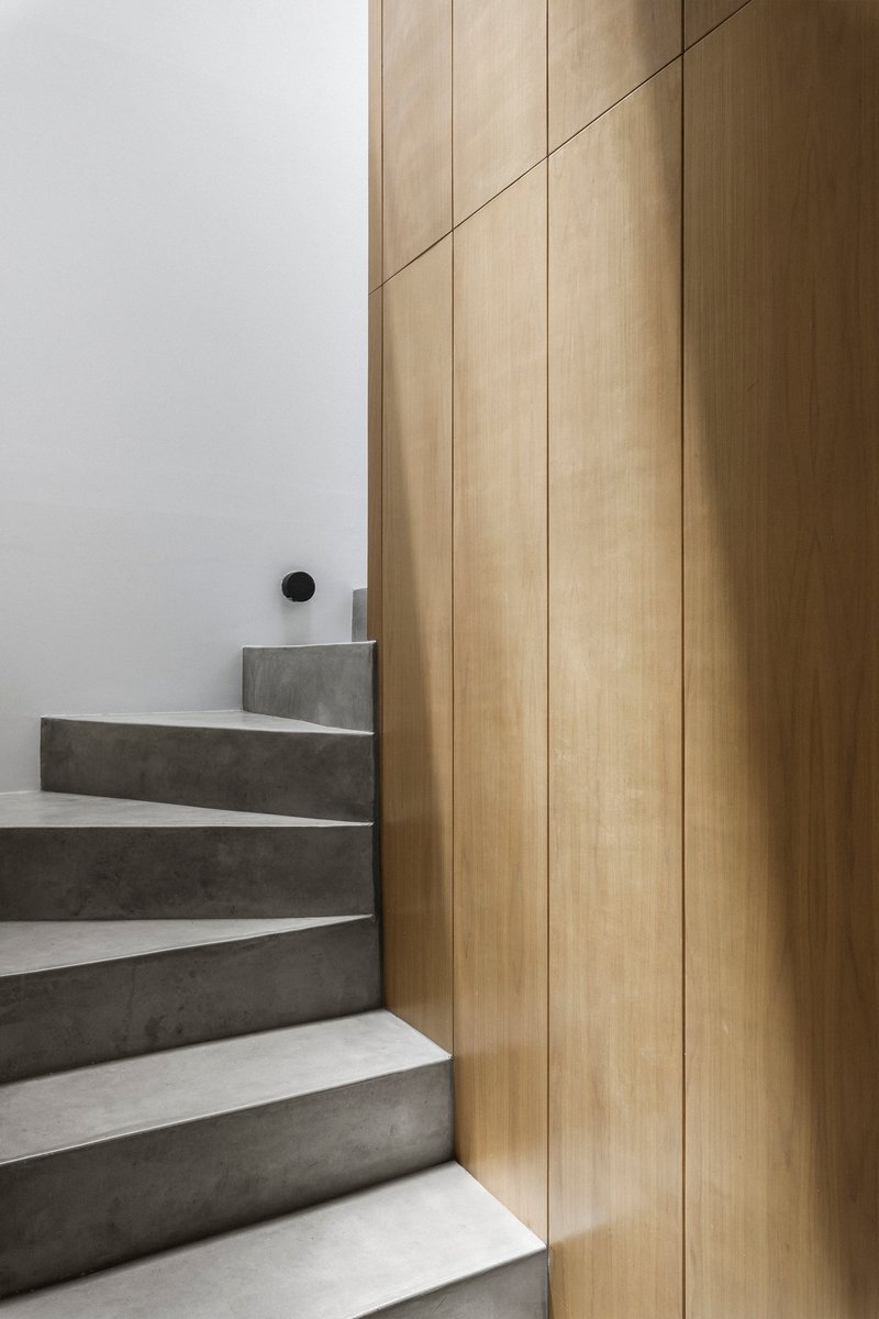 Concrete staircase with white risers meeting a vertical oak paneled wall