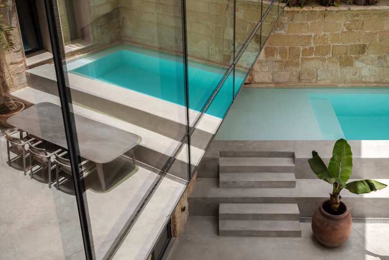 Swimming pool terrace with glass balustrade, concrete steps and potted banana plant