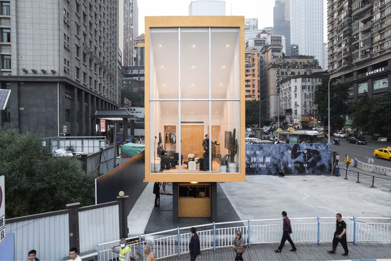 Three-story pavilion with translucent facade and timber frame set in an urban plaza with pedestrians passing by