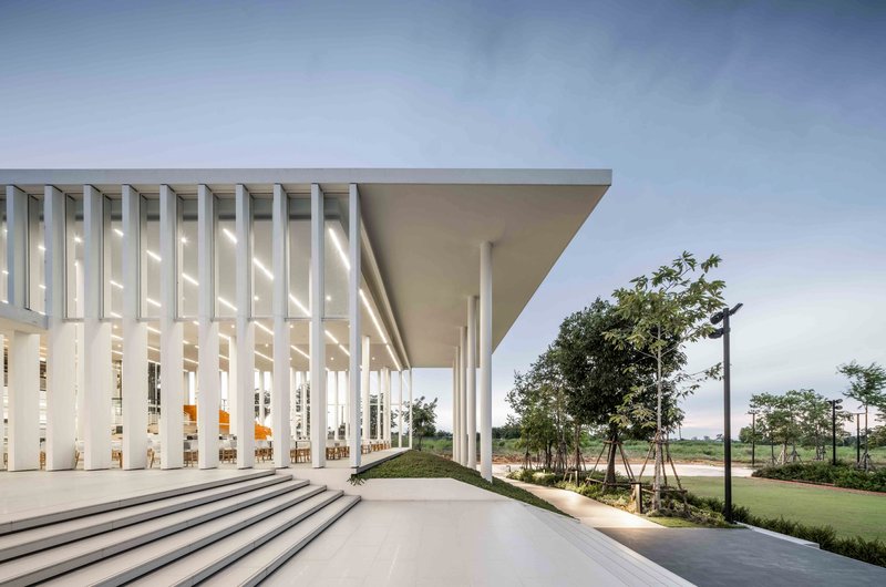 Covered entry plaza with white vertical louvers and deep overhang supported by slender columns