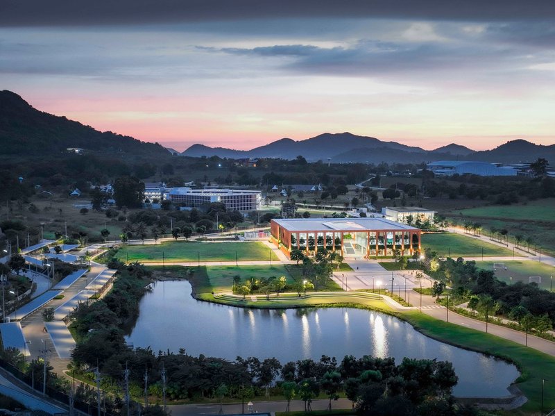 Dusk view of the illuminated complex beside a reflecting pond with mountain silhouettes beyond
