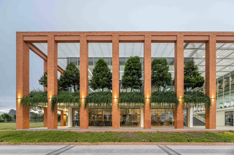 Timber frame facade with planted green terrace beneath vertical louvers illuminated at twilight