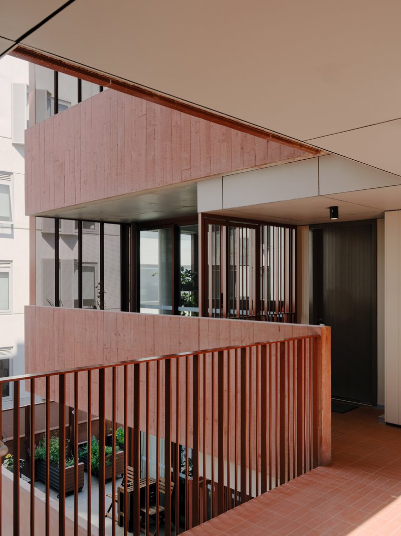 Multi-level circulation space with pink timber slat balustrades and planted beds at ground level