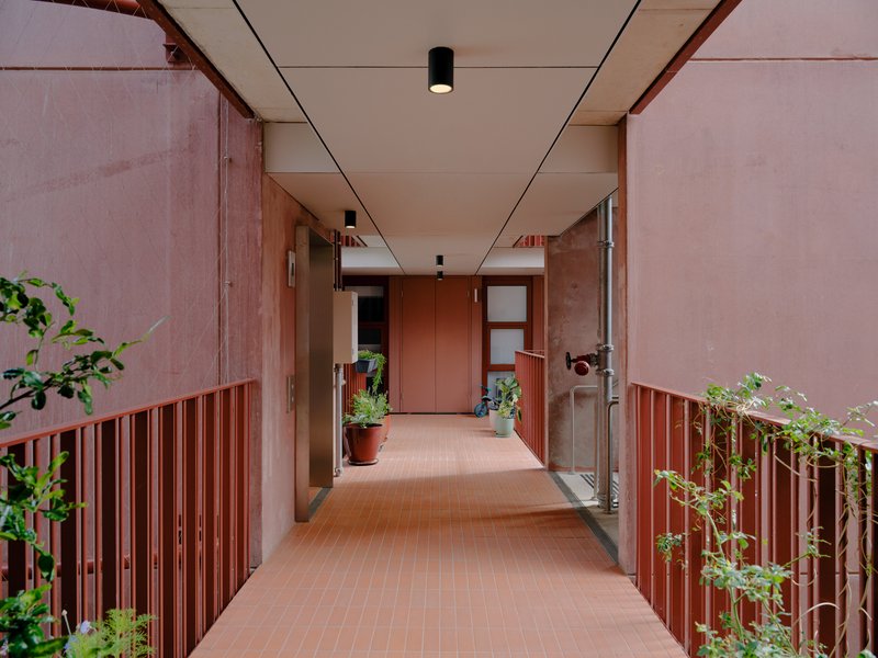 Corridor with pink vertical slat railings and planters on both sides under a recessed panel ceiling